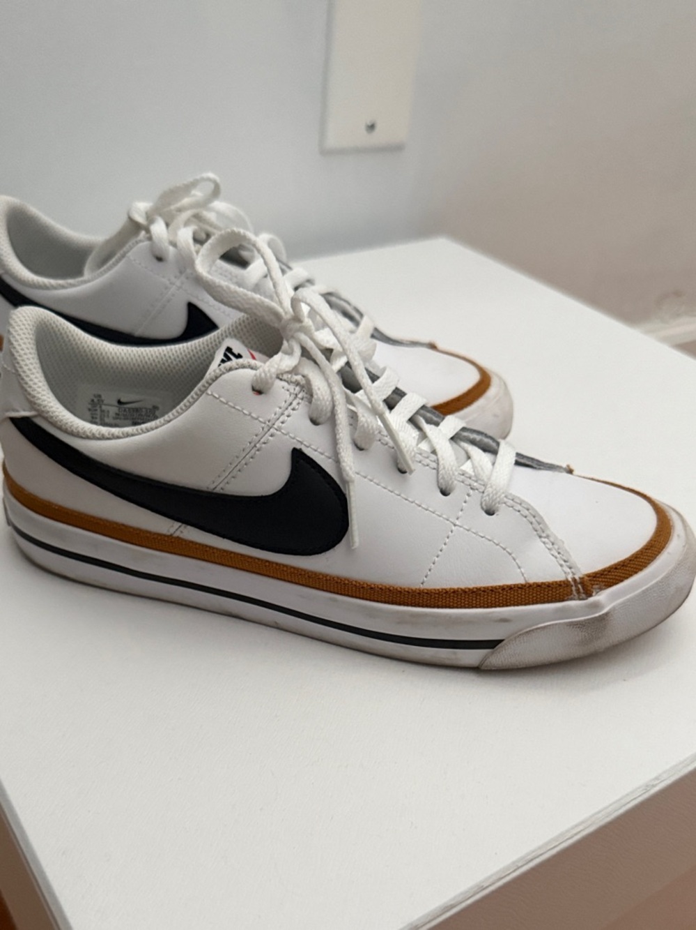 Nike White Low-Top Sneakers with Black Swoosh and Brown/Gold Accent